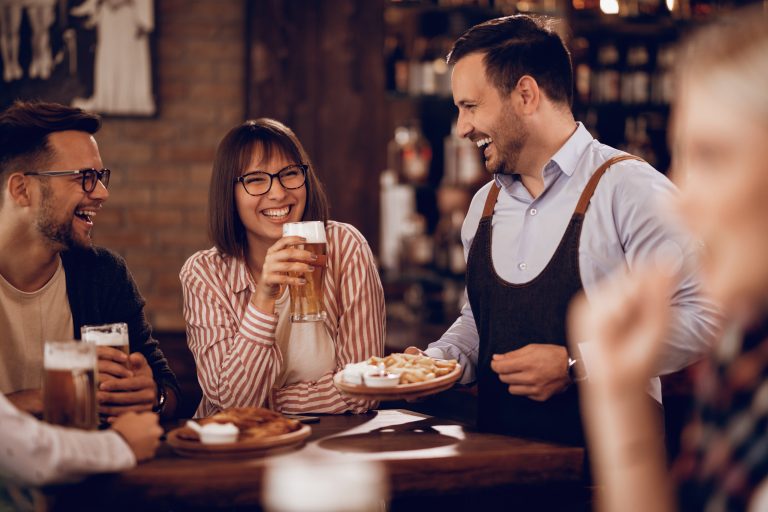 uśmiechnięci klienci w restauracji pijący piwo kelner serwujący danie Niemiecki w podróży Wakacje i komunikacja w języku niemieckim Preston Publishing