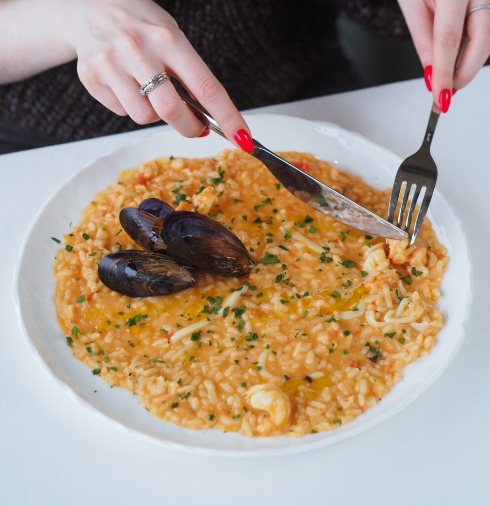 hiszpańska paella na talerzu jedzona przez kobietę Hiszpańskie tradycje i zwyczaje Preston Publishing
