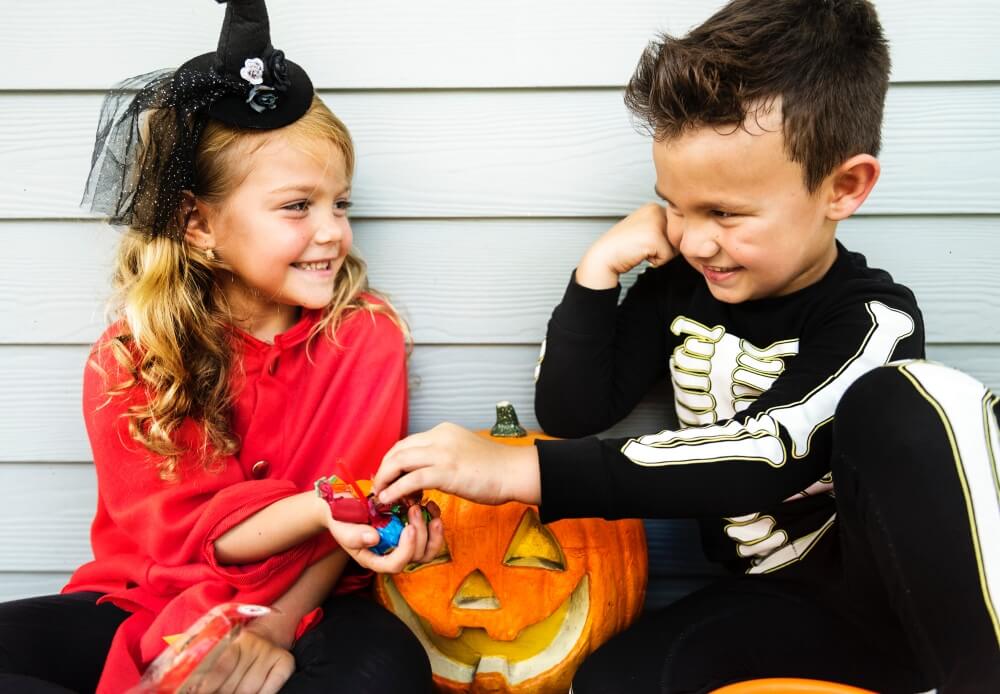 dziewczynka i chłopiec siedzą przy ścianie i przebrani są w halloweenowe stroje a w rękach maja dynie halloweenowe słownictwo Preston Publishing