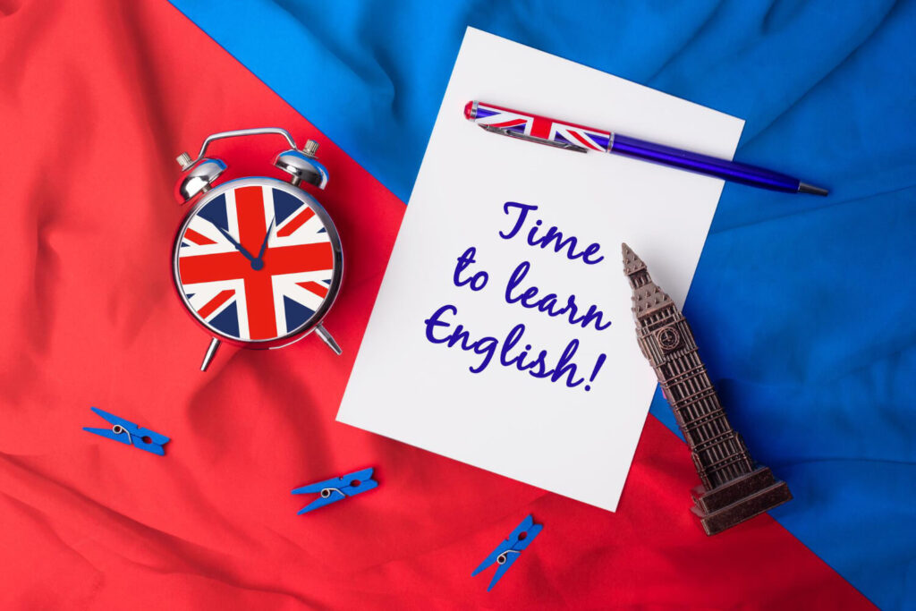 na czerwono niebieskim materiale zegar z flaga brytyjska oraz figurka Big Bena oraz notes z napisem time to learn english nauka języka angielskiego z Preston Publishing