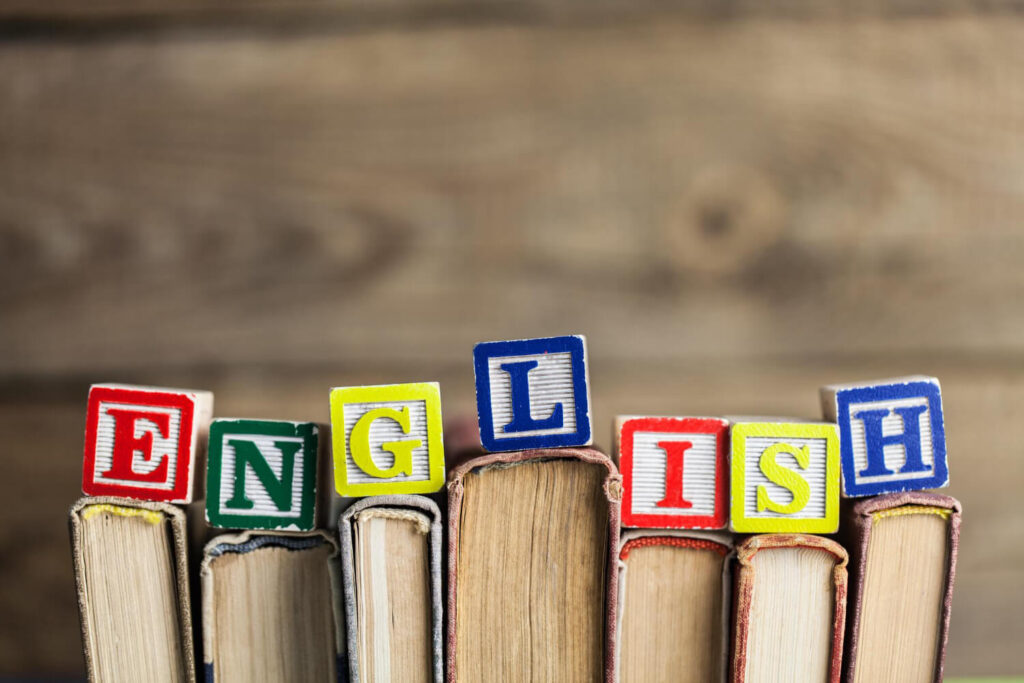 klocki z kolorowymi literami układającymi się w wyraz english ustawione na grzbietach książek nauka języka angielskiego Preston Publishing