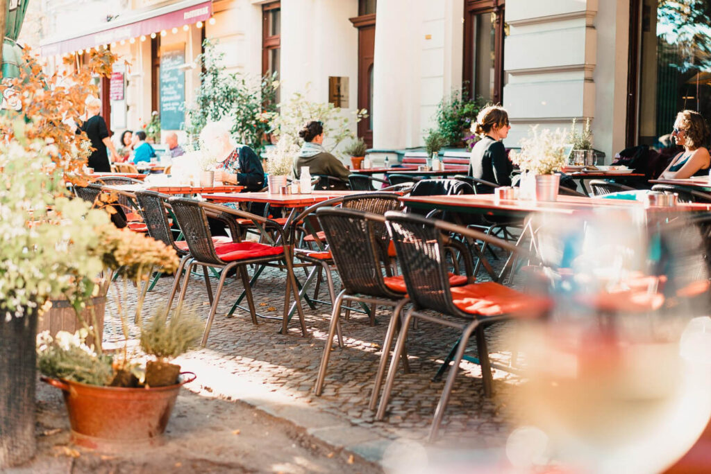 widok na stoliki w restauracji ustawione na ulicy, widać siedzących ludzi, zwroty hiszpańskie w restauracji Preston Publishing