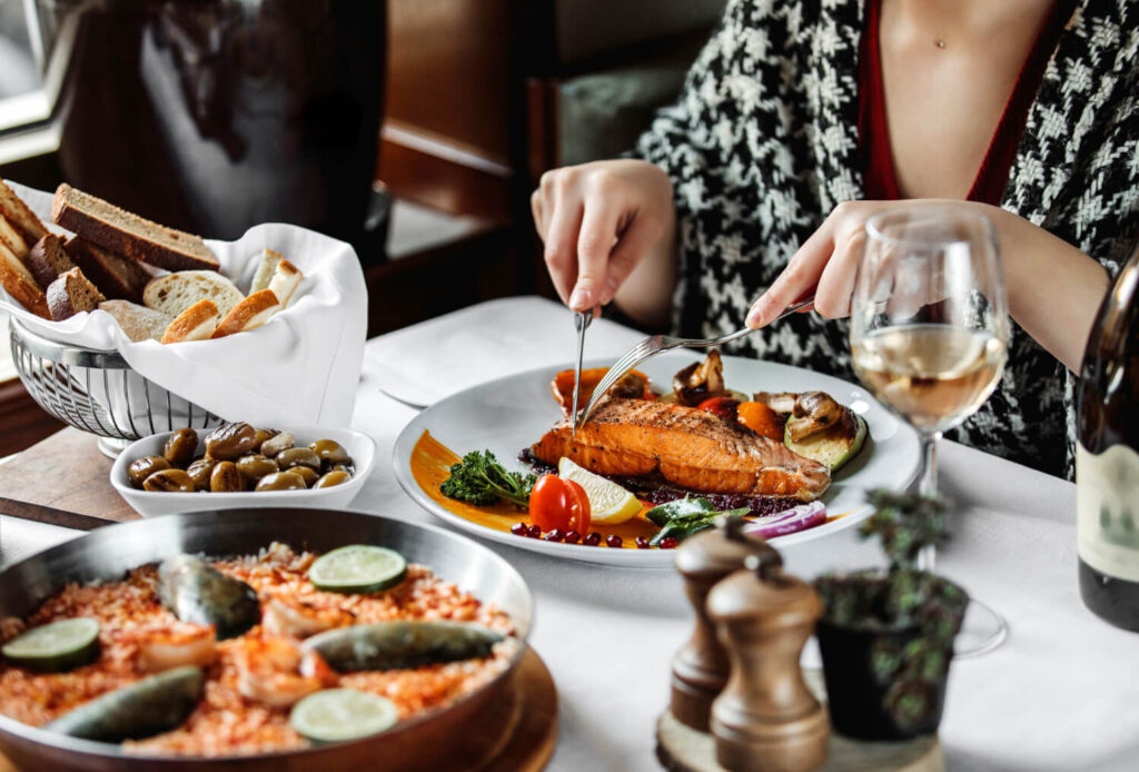 kobieta rozpoczynająca jedzenie zamówionego posiłku w restauracji na stole jest tez paella zamawianie posiłków i napojów w restauracji po hiszpańsku Preston Publishing