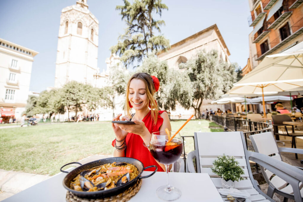 dziewczyna w czerwonej sukience siedząca w restauracji przy stoliku z podana paella i sangria zamawianie posiłków po hiszpańsku Preston Publishing
