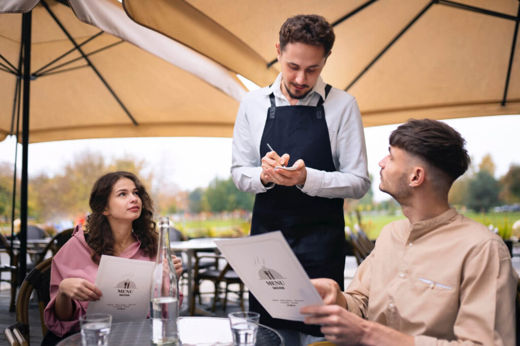 kelner przyjmujący zamowienie w restauracji od pary zamawianie posiłków i napojów po hiszpańsku Preston Publishing