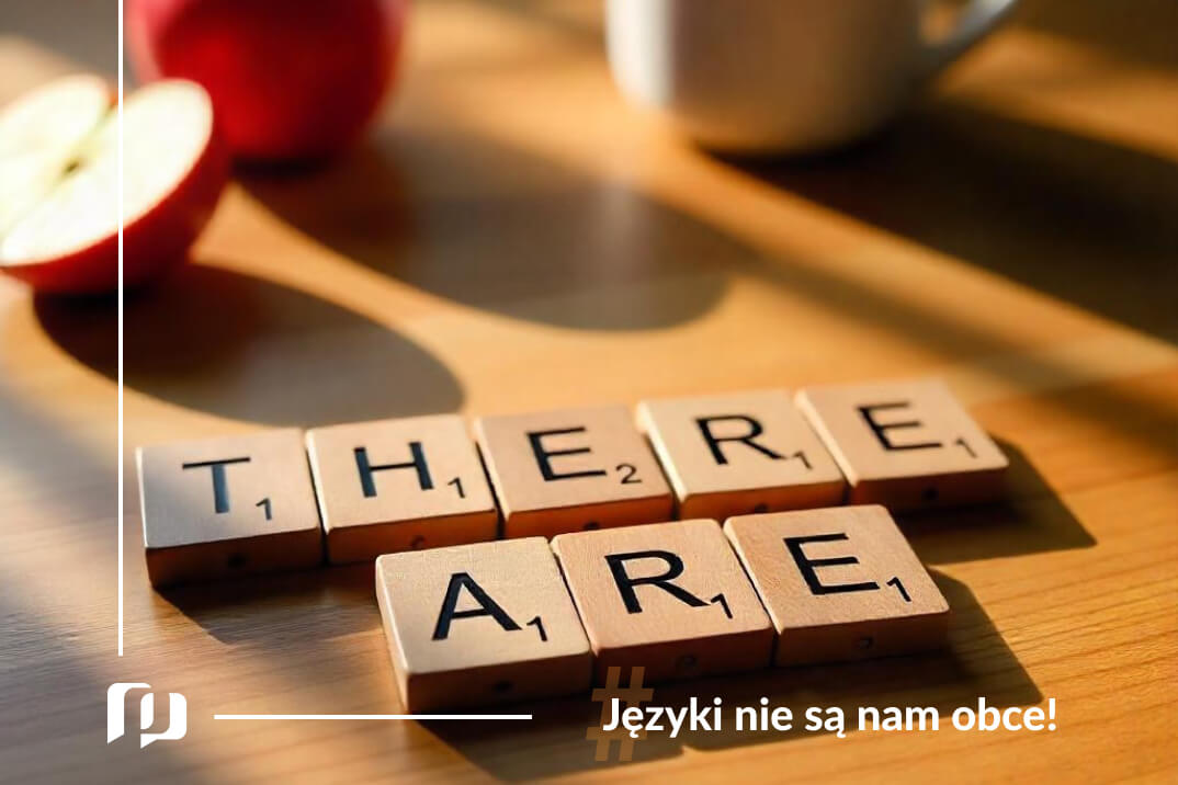 Klocki z literkami ułożonymi w wyrażenie there are leżące na drewnianym biurku obok dwóch połówek jabłka nauka angielskiego z Preston Publishing Angielski od zera w 180 dni