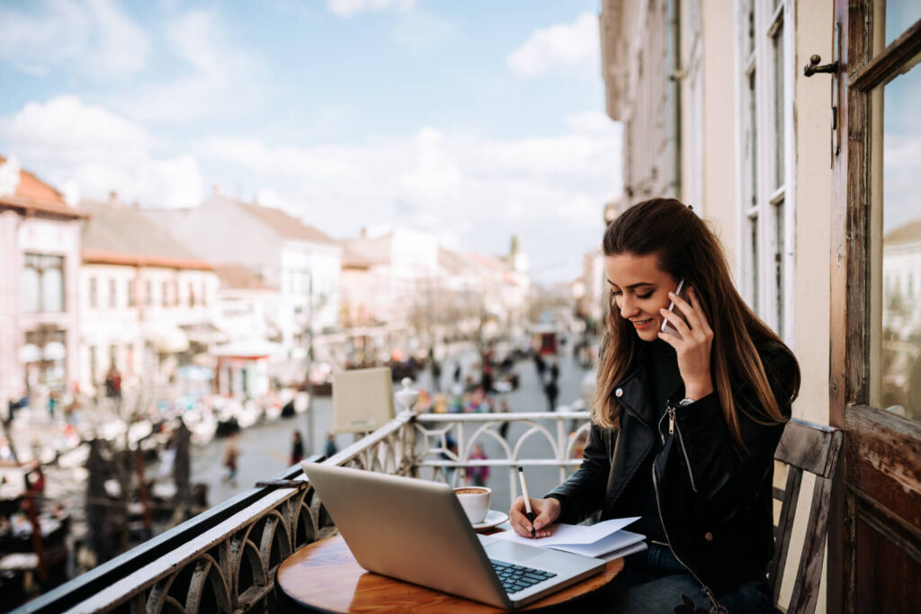 kobieta negocjującą cos przez telefon siedząca na balkonie przed laptopem nauka hiszpańskiego Preston Publishing
