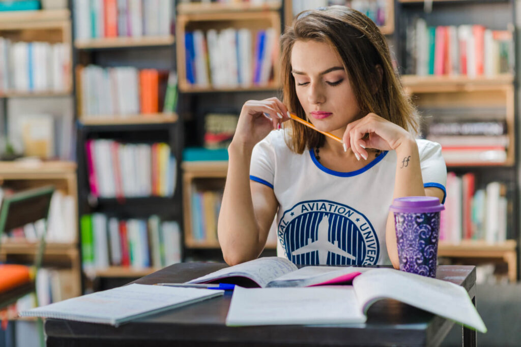 dziewczyna w bibliotece ucząca się z książek i zeszytów Preston Publishing Francuski w tłumaczeniach gramatyka