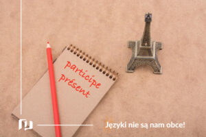 na bezowym tle notes z napisem participe present I czerwony ołówek oraz wieża Eiffla - imiesłów czasu teraźniejszego w języku francuskim nauka języków z Preston Publishing