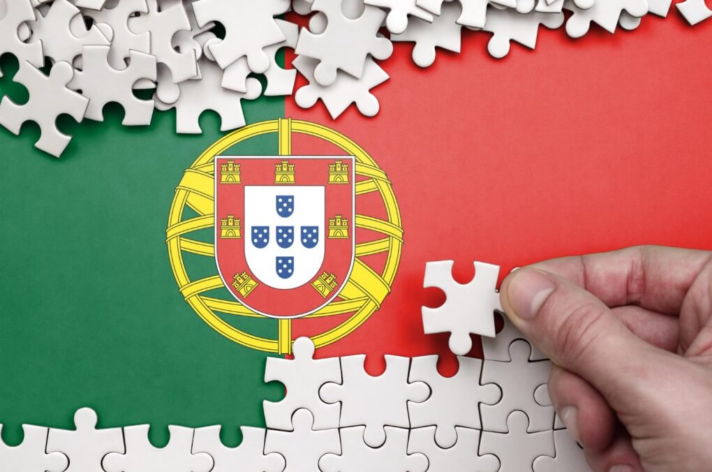 portugalska flaga na której ktoś układa białe puzzle nauka portugalskiego od podstaw PRESTON PUBLISHING