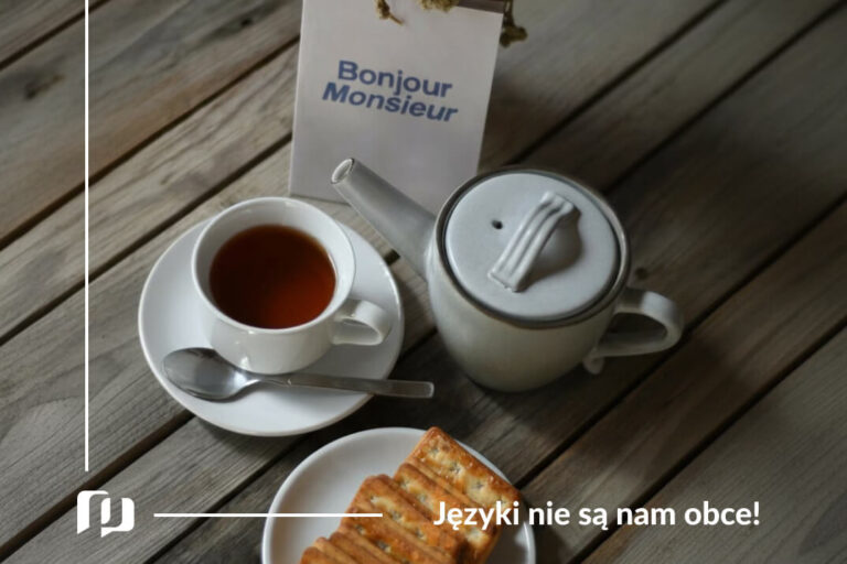 na stole filiżanka z herbata, croissant oraz cukiernica, a obok karteczka z napisem bonjour monsieur podstawowe zwroty po francusku powitania i pożegnania Preston Publishing