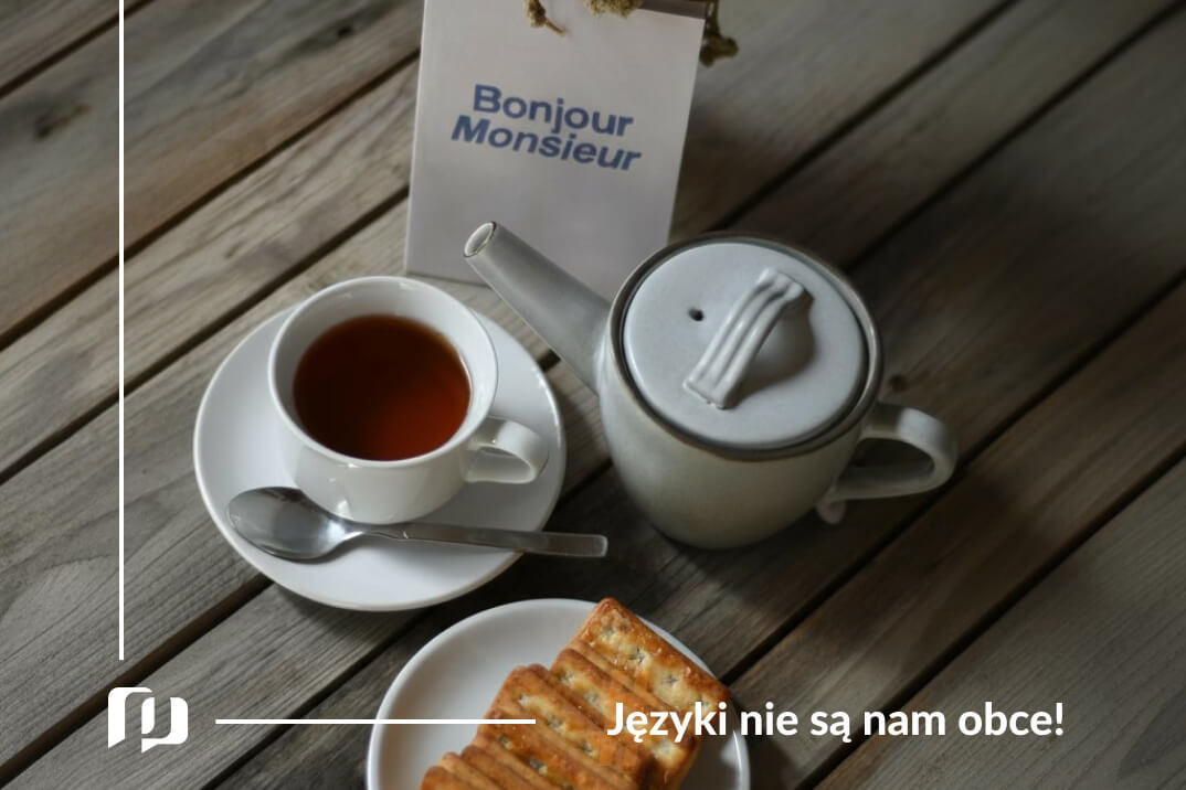 na stole filiżanka z herbata, croissant oraz cukiernica, a obok karteczka z napisem bonjour monsieur podstawowe zwroty po francusku powitania i pożegnania Preston Publishing