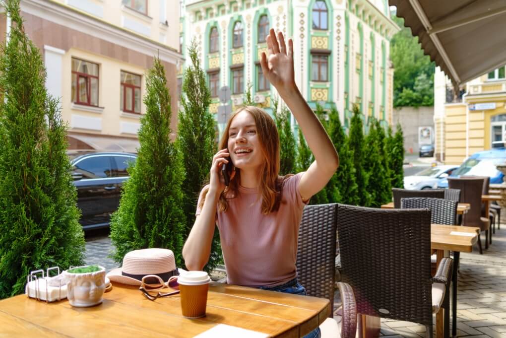 dziewczyna w kawiarni z podniesiona ręką witająca kogoś z daleka powitania i pożegnania po francusku Preston Publishing