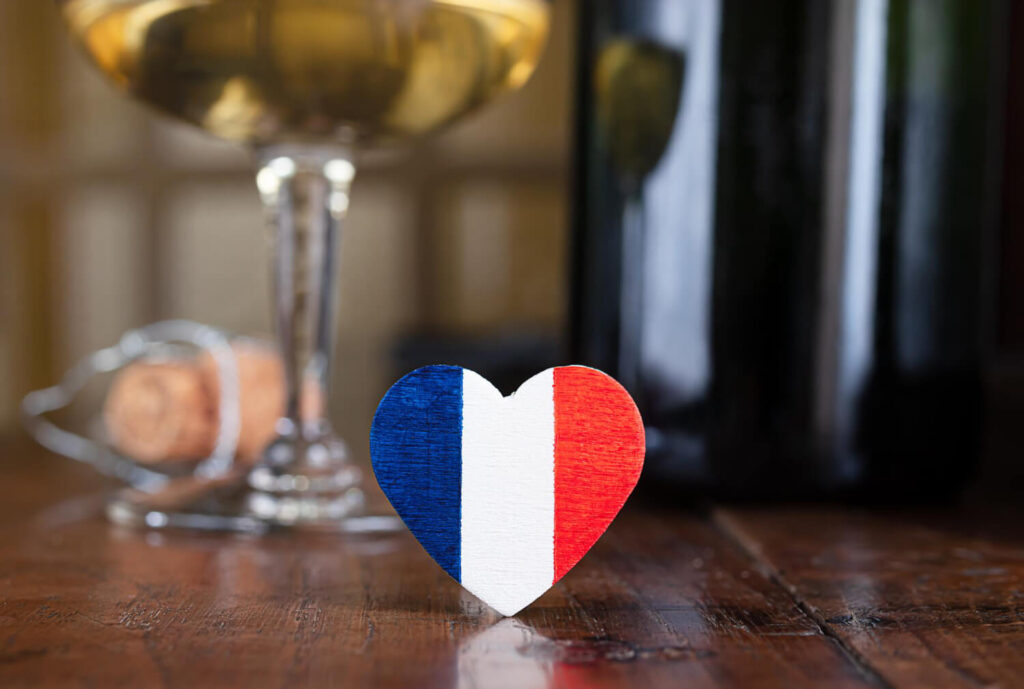 serduszko z francuska flaga na stoliku a w tle kieliszek przydatne zwroty po francusku Preston Publishing