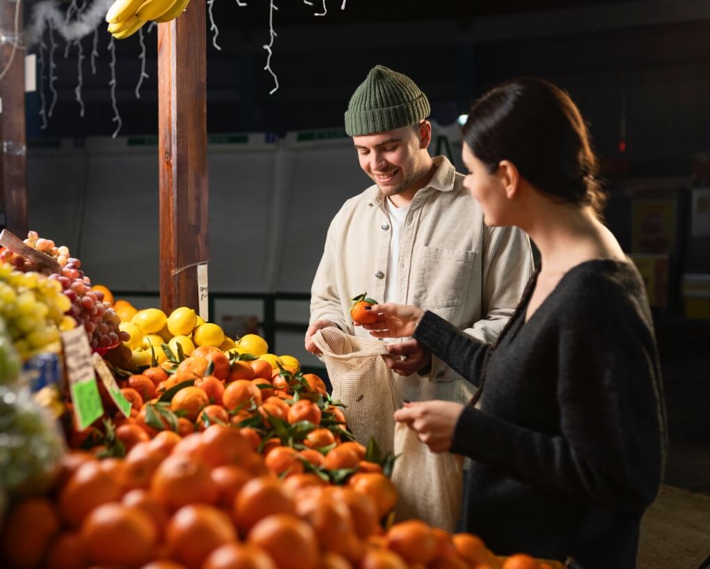 na straganie kobieta wybiera owoce a mężczyzna pakuje je do siatki nauka owoców po włosku z Preston Publishing
