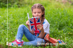 usmiechnieta dziewczynka siedzi na lace z zeszytem z flaga brytyjska uczaca sie jezyka angielskiego z Preston Publishing